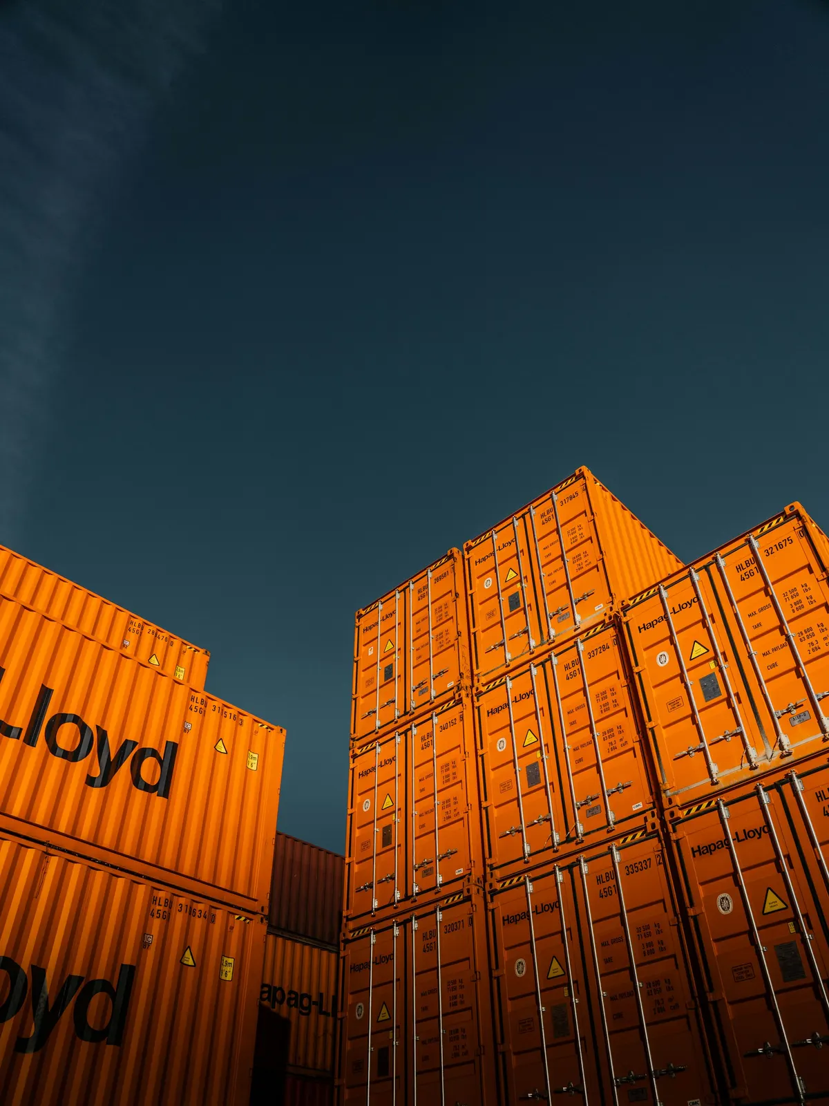 Stacked orange shipping containers against a dark sky